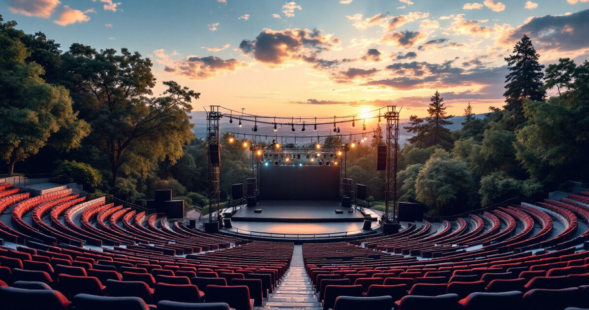 Outdoor amphitheatre stage at dusk with string lights and summer evening sky